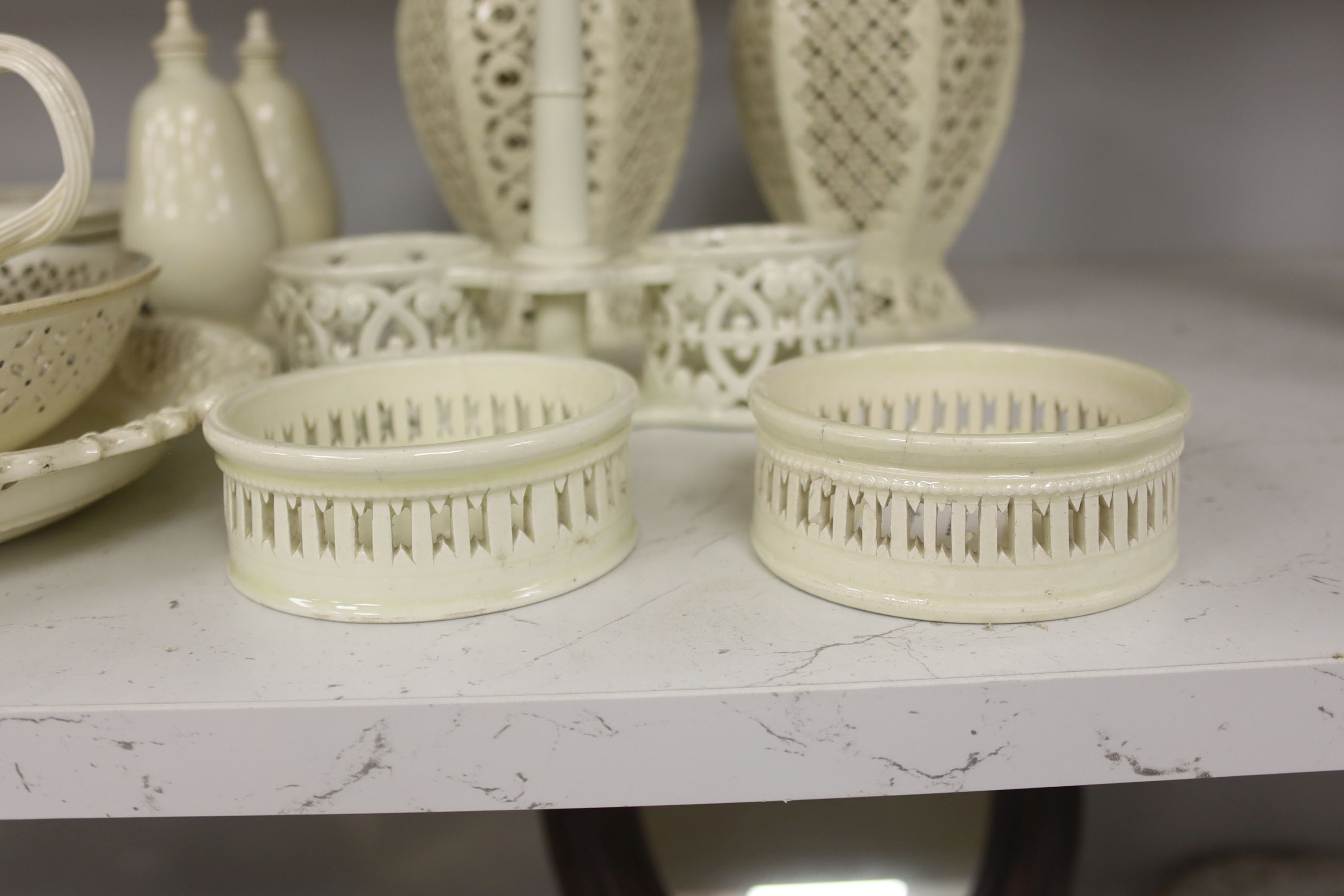 A collection of creamware, circa 1800, Staffordshire and Yorkshire comprising three pairs of plates, with moulded laurel swags, pair of small bottle coasters, sauceboat, saucer dish, two teacups, cruet stand, two pear sh